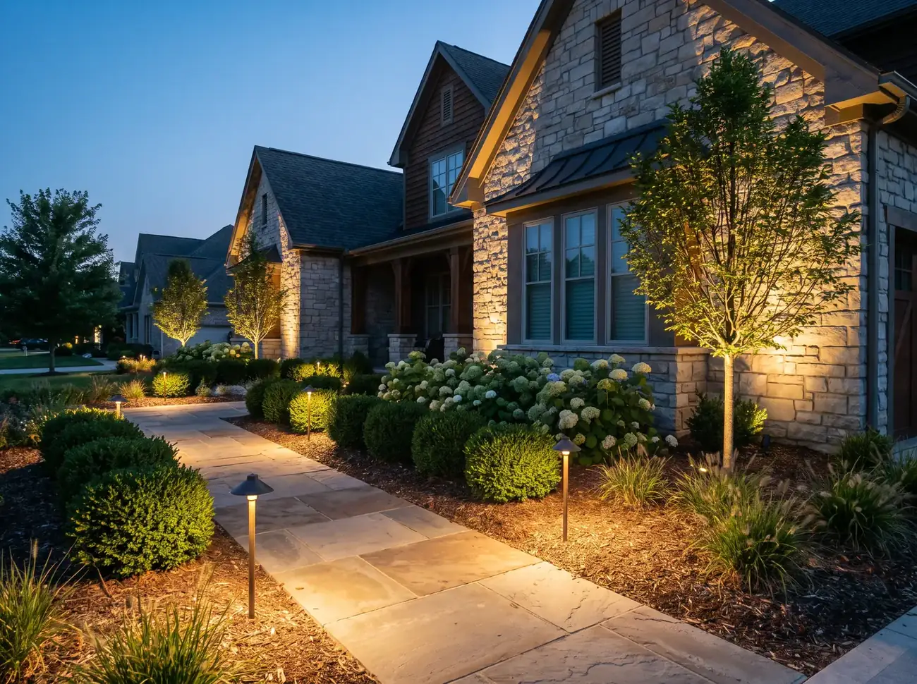 Landscape lighting illuminating a walkway and garden at dusk